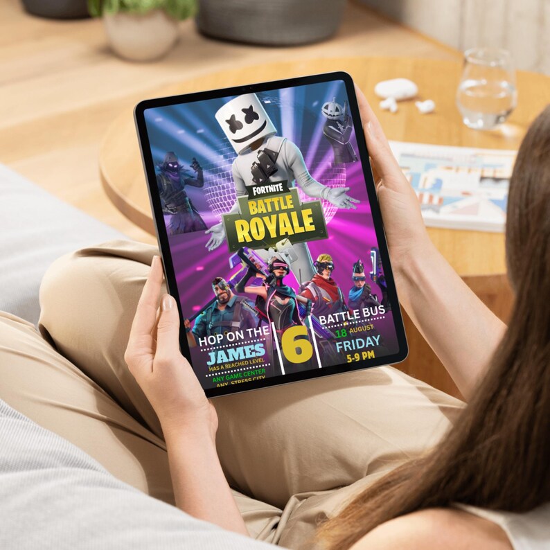 Może przedstawiać: Tablet z reklamą Fortnite Battle Royale. Reklama zawiera tekst "Fortnite Battle Royale", "Hop on the James" i "Battle Bus". Tło jest żywe fioletowo-niebieskie z ilustracjami postaci.