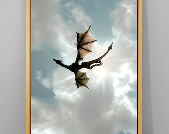 May include: A framed print featuring a dragon soaring through a cloudy sky. The dragon is silhouetted against the sun, with its wings spread wide. The artwork is set in a light brown wooden frame, creating a fantasy theme.