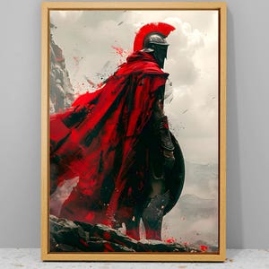 May include: A framed canvas print depicts a Spartan warrior in full armor, viewed from the back, standing on a rocky precipice. The warrior wears a red cape and helmet with a red plume, holding a shield. The background features a cloudy sky and mountains.