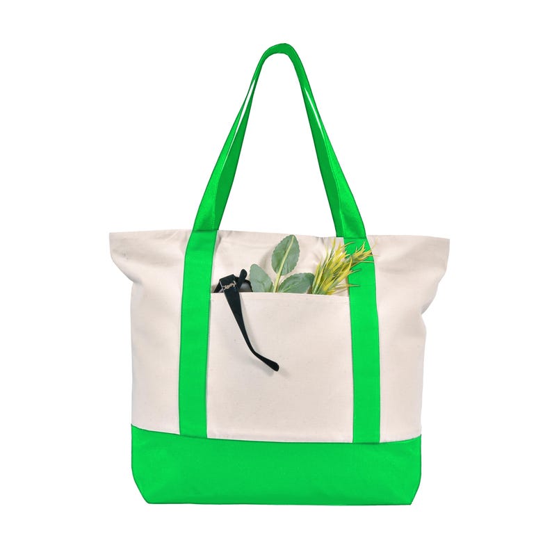 May include: A canvas tote bag with a cream-colored body and a bright green base and straps. The bag has a front pocket containing greenery and a pair of sunglasses. The bag is designed for carrying items.