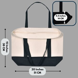 May include: A canvas tote bag with a cream-colored body and a black base and handles. The bag is 20 inches (51 cm) wide, 15 inches (38 cm) tall, and 5.5 inches (14 cm) deep. It has a zipper closure and is designed for carrying items.
