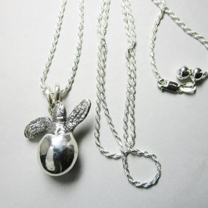 Może przedstawiać: Srebrny naszyjnik z łańcuszkiem w kształcie liny i srebrnym wisiorem w kształcie żółwia. Wisiorek jest ozdobiony detalami w postaci skorupy żółwia i płetw.