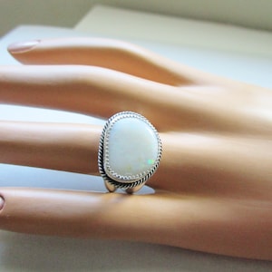 May include: A silver ring with a white opal gemstone set in a rope-like design.