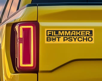 May include: A yellow truck with a black and yellow bumper sticker that reads "Filmmaker. But Psycho."
