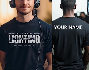 May include: Black t-shirt with white text that reads "KEEP GLOWING STAY ILLUMINATED LIGHTING PRECISION MASTER". The back of the shirt has white text that reads "YOUR NAME".