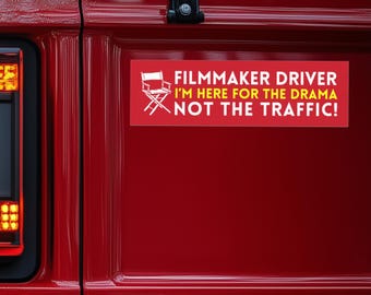 May include: Red car with a white and yellow bumper sticker that reads "Filmmaker Driver I'm here for the drama not the traffic!" with a director's chair icon.