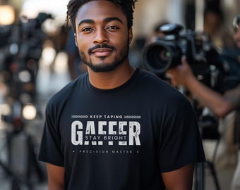 May include: A black t-shirt with a white graphic that says "Gaffer Keep Taping Stay Bright Precision Master".