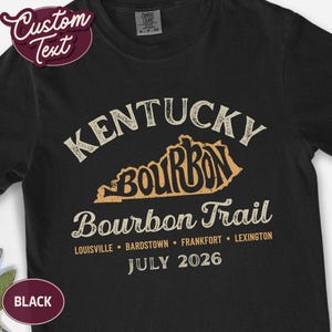A black t-shirt with "KENTUCKY BOURBON TRAIL" and a map of Kentucky printed in distressed cream-colored text, with "Louisville, Bardstown, Frankfort, Lexington" and "JULY 2026" below.