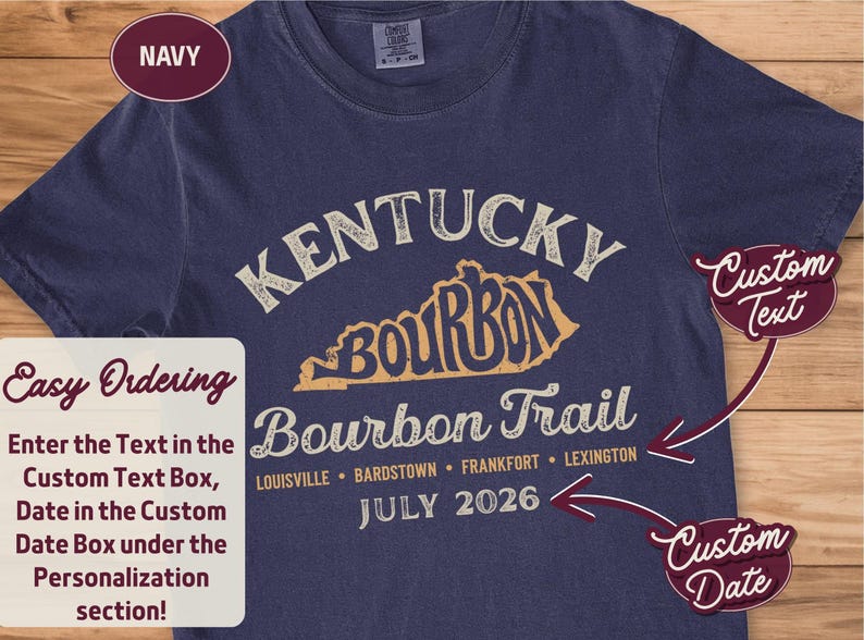 May include: A navy blue short-sleeve t-shirt featuring a graphic with the text Kentucky Bourbon Trail, a map outline, and city names including Louisville, Bardstown, Frankfort, and Lexington. The design includes the date July 2026 in white text.