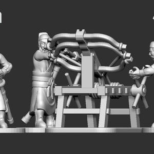 Op de afbeelding: Een 28 mm miniatuurmodel dat drie figuren toont die een belegeringswapen bedienen. De figuren zijn gekleed in historische kledij. Het model is gelabeld met "Ten Kingdoms".