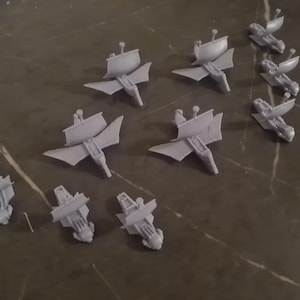 Puede incluir: Una colección de diez modelos de barcos de plástico gris con velas. Los barcos son todos del mismo diseño, pero están en diferentes etapas de montaje.