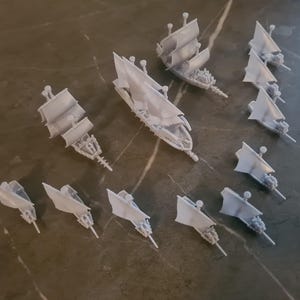 Puede incluir: Una colección de 12 barcos en miniatura blancos con velas, perfectos para juegos de mesa o para exhibir. Los barcos están hechos de plástico y tienen detalles intrincados.