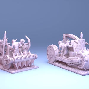 May include: Two miniature fantasy siege engines, possibly for tabletop gaming. One is a catapult with figures, the other a spiked roller. Both are light purple and set against a blue gradient background. The models appear to be 3D printed.