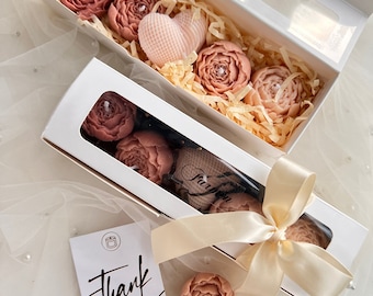 May include: Two white gift boxes filled with pink and peach floral scented candles. The boxes are tied with a cream-colored ribbon and a thank you card is included.