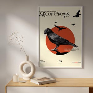 May include: A poster with a black and white illustration of a crow on a red circle. The poster has the text "Six of Crows" in a stylized font and the text "Six dangerous outcasts, one impossible heist".