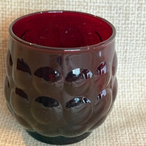 May include: A white ceramic mug with a black handle and the text "But First, Coffee" in a bold, black font. The mug is set against a blurred background, suggesting a cozy setting.