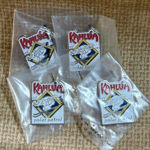 May include: Four Kahlua "polar patrol" pins in clear plastic packaging. Each pin features the Kahlua logo in red, a blue and yellow diamond, and the words "polar patrol". The pins are made in Taiwan.