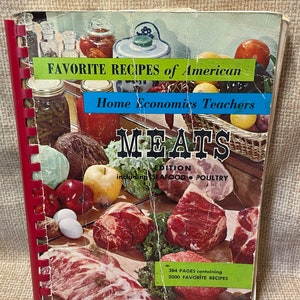 May include: A red spiral bound cookbook titled "Favorite Recipes of American Home Economics Teachers: Meats Edition, including Seafood & Poultry". The cover features a variety of fresh ingredients, including vegetables, fruits, eggs, and raw meat.