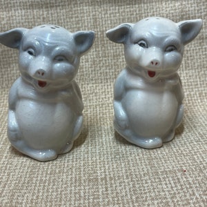 May include: A pair of ceramic pig salt and pepper shakers. The pigs are white with gray accents and have a playful expression on their faces.