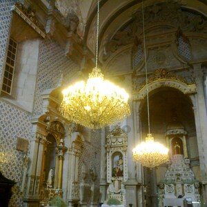 Puede incluir: Una gran l&aacute;mpara de ara&ntilde;a de cristal ornamentada cuelga del techo de una iglesia. La l&aacute;mpara de ara&ntilde;a est&aacute; iluminada y proyecta un c&aacute;lido resplandor en el &aacute;rea circundante. La iglesia tiene un techo abovedado alto y decoraciones ornamentadas.