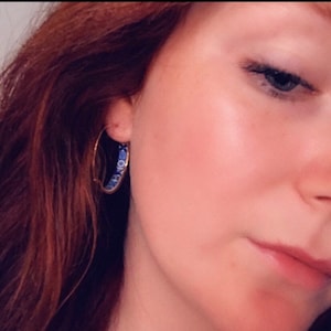 May include: A pair of gold hoop earrings with a blue and white patterned design.