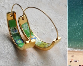 May include: A pair of gold hoop earrings with a green and white patterned design. The pattern features small floral and geometric shapes.