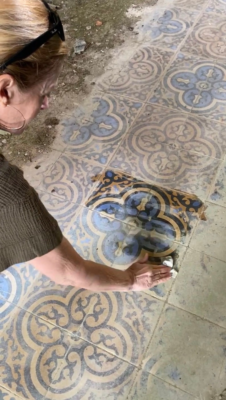 Peut inclure: Une personne nettoie un sol carrel&eacute; avec un chiffon blanc. Les carreaux sont de couleur bleue et jaune avec des motifs complexes. Le sol est sale et doit &ecirc;tre nettoy&eacute;.