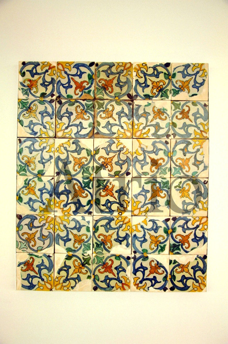 May include: A collection of 25 square ceramic tiles with a repeating pattern of blue, yellow, and orange floral designs. The tiles are arranged in a grid pattern.
