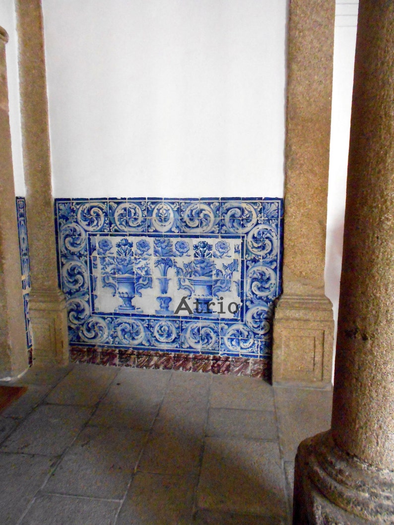 Peut inclure: Un mur blanc avec une bordure de carreaux bleus et blancs. Les carreaux ont un motif floral et sont dispos&eacute;s de mani&egrave;re sym&eacute;trique. Un pilier en pierre se trouve au premier plan.