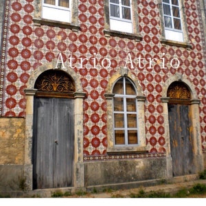 May include: A building with a red and white tiled facade. The building has three arched windows and three arched doorways. The text "Atrio Atrio" is written in white letters on the facade.