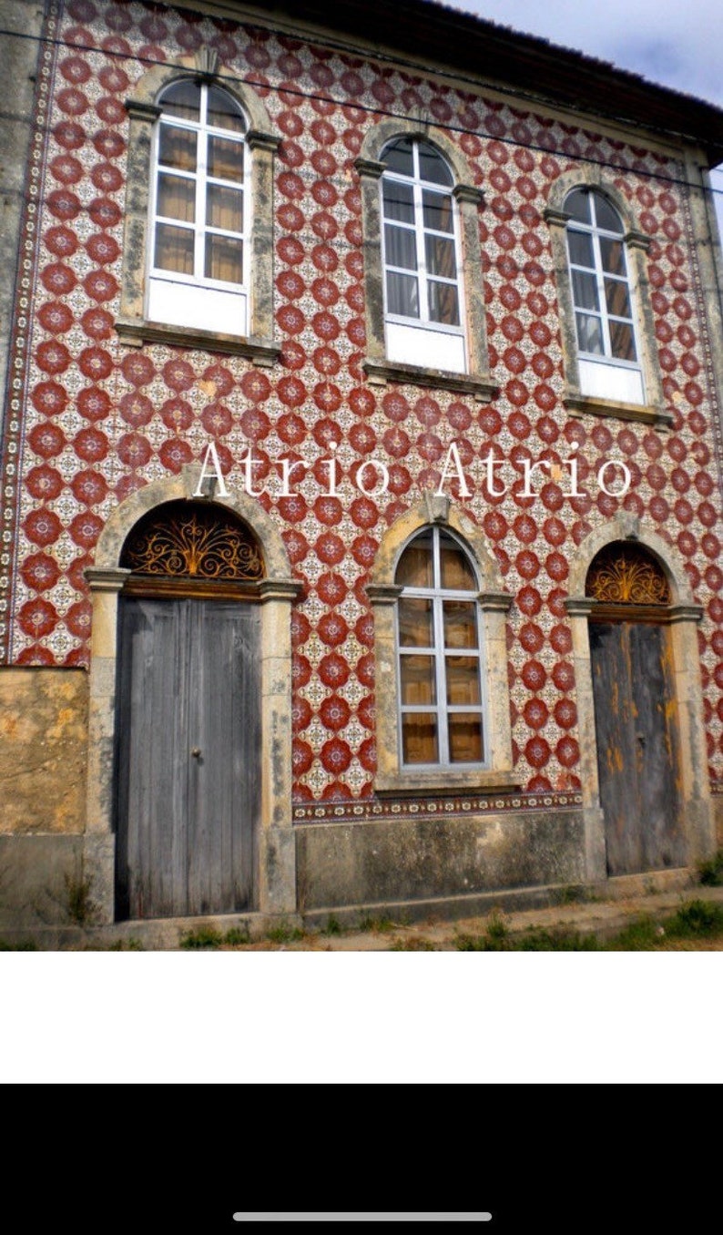 May include: A building with a red and white tiled facade. The building has three arched windows and three arched doorways. The text "Atrio Atrio" is written in white letters on the facade.