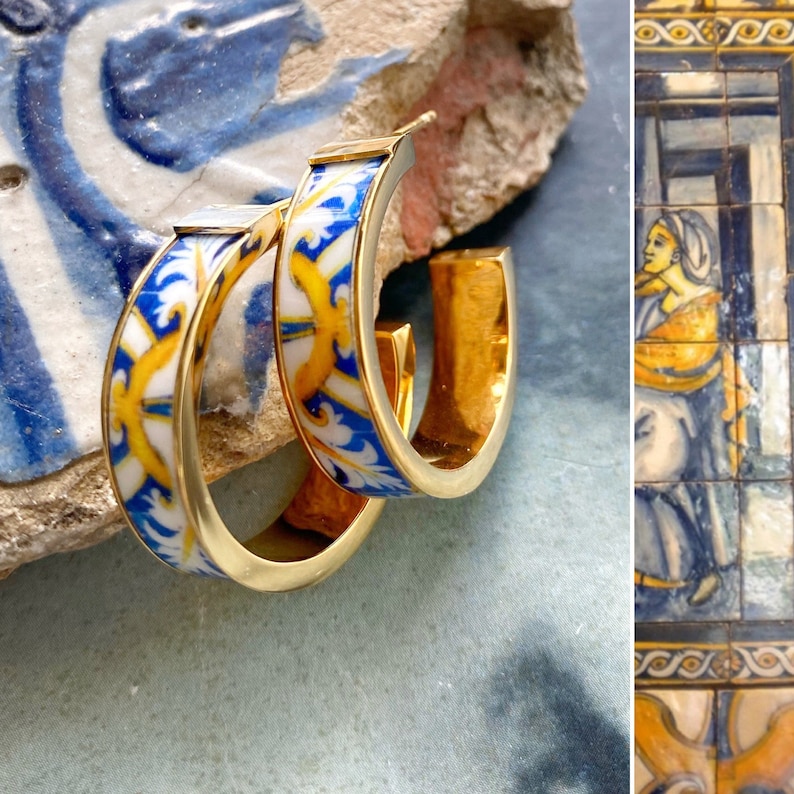 Op de afbeelding: Een paar gouden creolen met blauwe en witte gepatroneerde keramische inlegstukken. Het patroon heeft een gestileerd bloemenmotief.