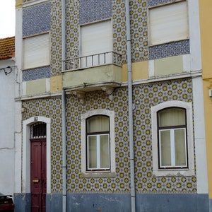 Peut inclure: Un b&acirc;timent avec une fa&ccedil;ade en carrelage. Les carreaux sont de couleur jaune et bleue. Il y a trois fen&ecirc;tres avec des volets blancs et une porte rouge. Le b&acirc;timent poss&egrave;de un balcon avec une balustrade blanche.