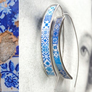 May include: A pair of silver hoop earrings with a blue and white patterned design. The pattern is reminiscent of traditional Portuguese tiles.