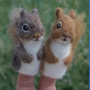 May include: Two handmade finger puppets shaped like squirrels. One is brown and gray, the other is reddish-brown. Both have white bellies and are made of soft, textured material. The puppets are designed to fit over fingers, with detailed facial features.