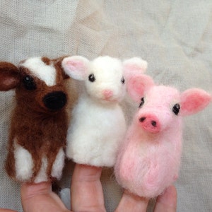 Pode incluir: Tr&ecirc;s fantoches de dedo de feltro: uma vaca marrom e branca, um cordeiro branco e um porco rosa. A vaca tem nariz e olhos pretos, o cordeiro tem orelhas rosas e o porco tem focinho rosa. Os fantoches s&atilde;o projetados para dedos.