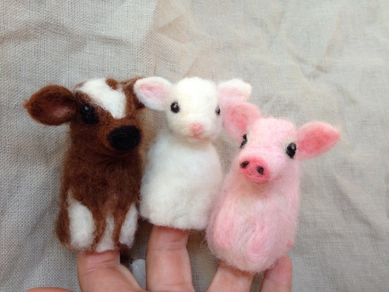 Pode incluir: Tr&ecirc;s fantoches de dedo de feltro: uma vaca marrom e branca, um cordeiro branco e um porco rosa. A vaca tem nariz e olhos pretos, o cordeiro tem orelhas rosas e o porco tem focinho rosa. Os fantoches s&atilde;o projetados para dedos.