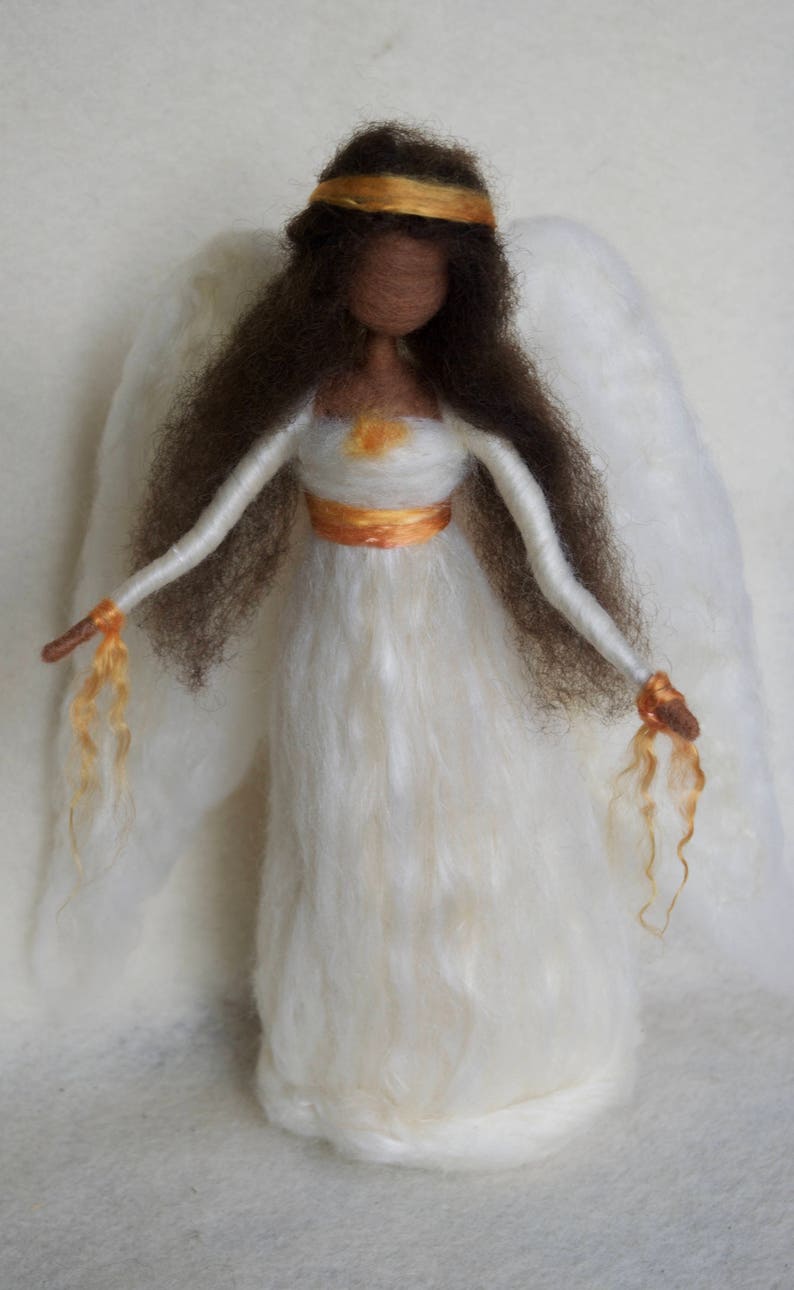 May include: A white felt angel doll with brown hair, a gold crown, and white wings. The angel is wearing a white dress with a gold sash.