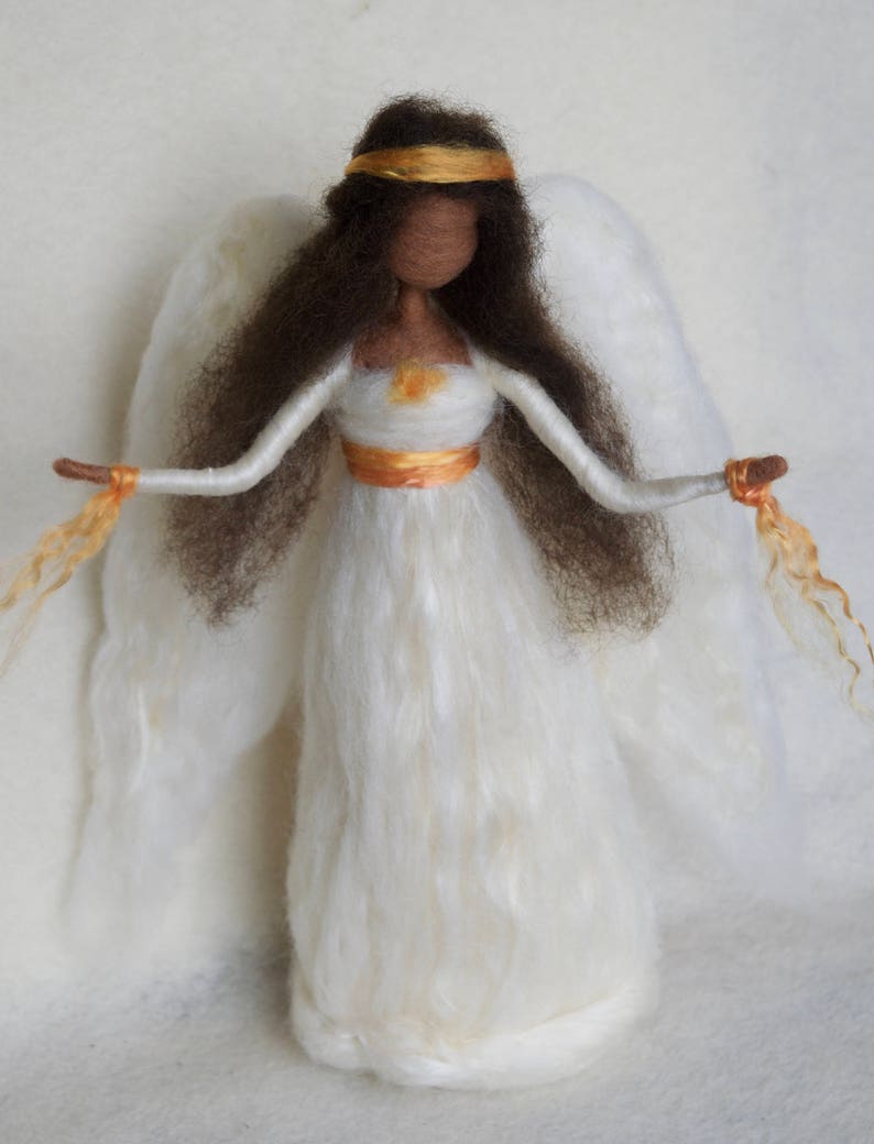 May include: A white felt angel doll with brown hair, a gold headband, and a white dress with a gold sash. The angel has white wings and is holding golden strands in each hand.