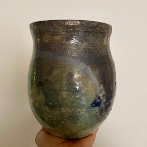 May include: A hand-thrown ceramic vessel with a bulbous shape and a wide, open mouth. The surface features a mottled glaze with deep tones of forest green, dark brown, and hints of navy blue, showcasing a textured, uneven finish throughout.