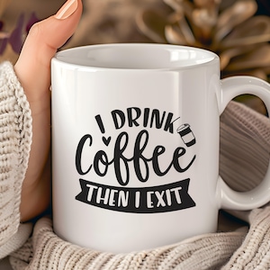 Könnte beinhalten: Weiße Keramik-Kaffeetasse mit dem Text "I Drink Coffee Then I Exit" in schwarzer Schrift. Die Tasse hat einen Henkel und eine kleine Kaffeetassen-Grafik. Die Tasse wird von einer Person gehalten, die einen cremefarbenen Pullover trägt.
