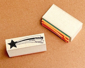 May include: Two wooden stamps with a black star and a rainbow design. The top stamp reads "twinkle twinkle twinkle".