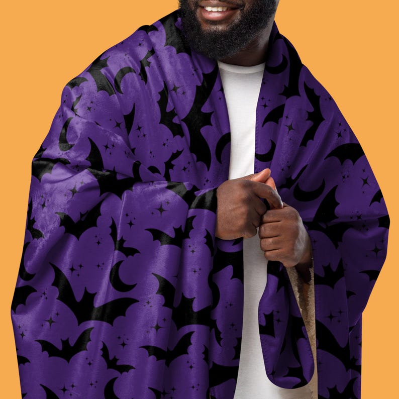 Image shows a man wearing a bat pattern sherpa fleece blanket called Bats In The Night. Color: Midnight Indigo. Available from HappyGlowLuckyCo.