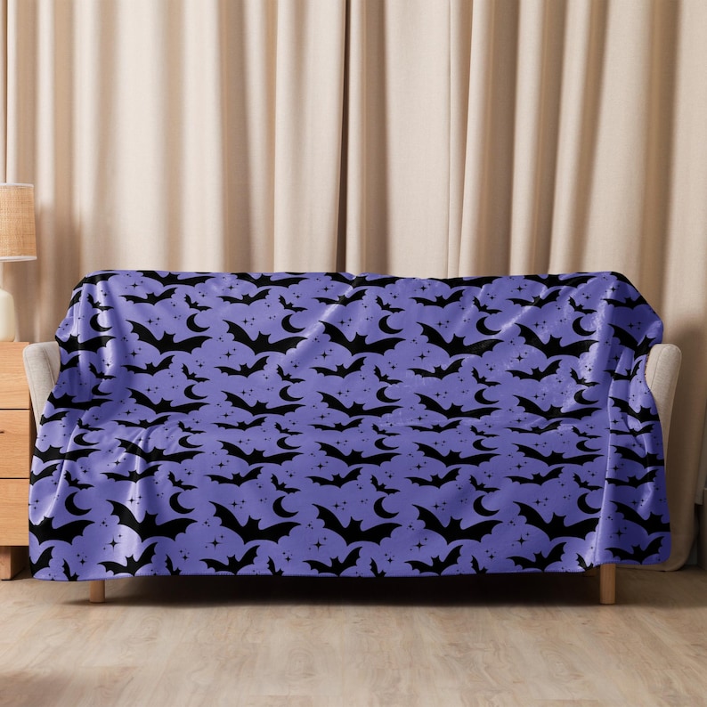 Image shows the 60inches x 80inches Bats In The Night Sherpa Fleece Blanket displayed on a couch. Color: Enchanted Lavender. Available from HappyGlowLuckyCo.