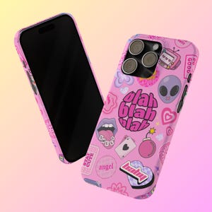 May include: Pink iPhone case with a variety of colorful stickers and graphics, including a cartoon alien, a heart, a bomb, and the words "blah blah blah".