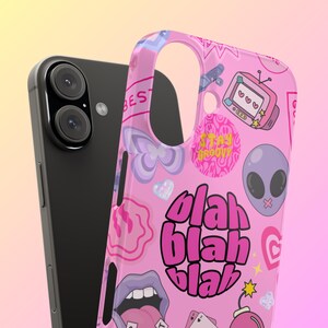 May include: A pink phone case with a variety of colorful stickers and graphics, including a pink and black circle with the text "blah blah blah", a purple alien, a pink heart, and a yellow star.