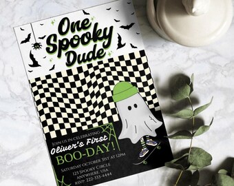 May include: A black and white checkered background with a ghost wearing a green hat and riding a skateboard. The text "One Spooky Dude" is at the top of the invitation. The text "Oliver's First BOO-DAY!" is in a green and white spiderweb design. The text "Saturday October 31st at 12pm 123 Spooky Circle Anywhere, USA RSVP: 222-333-4444" is at the bottom of the invitation.