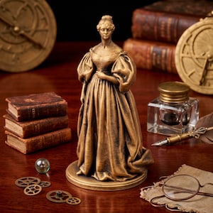 Puede incluir: Una figura de tono dorado que representa a una persona con un vestido largo y voluminoso de mangas abullonadas, sobre una base circular. La figura está rodeada de varios objetos, incluyendo pequeños engranajes metálicos, tres libros y un tintero.