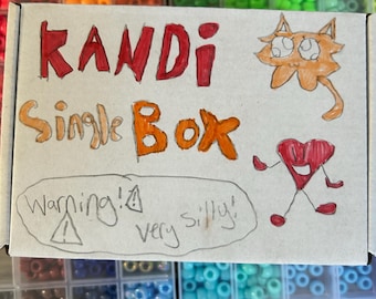 Può includere: Una scatola di cartone con la scritta "KANDI Single Box" in rosso e arancione, con un disegno di gatto e cuore dei cartoni animati. La scatola è circondata da contenitori pieni di perline colorate, tra cui arancione, verde e blu.