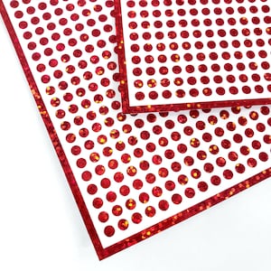 May include: Two sheets of red glitter paper with a white background and a repeating pattern of red circles.